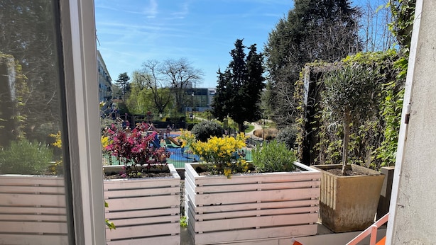 A balcony with a view of a playground and garden.