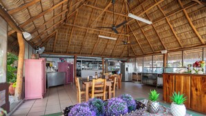 A spacious kitchen with wooden cabinets, a dining area with chairs, and a ceiling fan. - Torreblanca Beach Hotel and Suites Guayabitos - Desayuno y Comida Incluido (Rincón de Guayabitos)