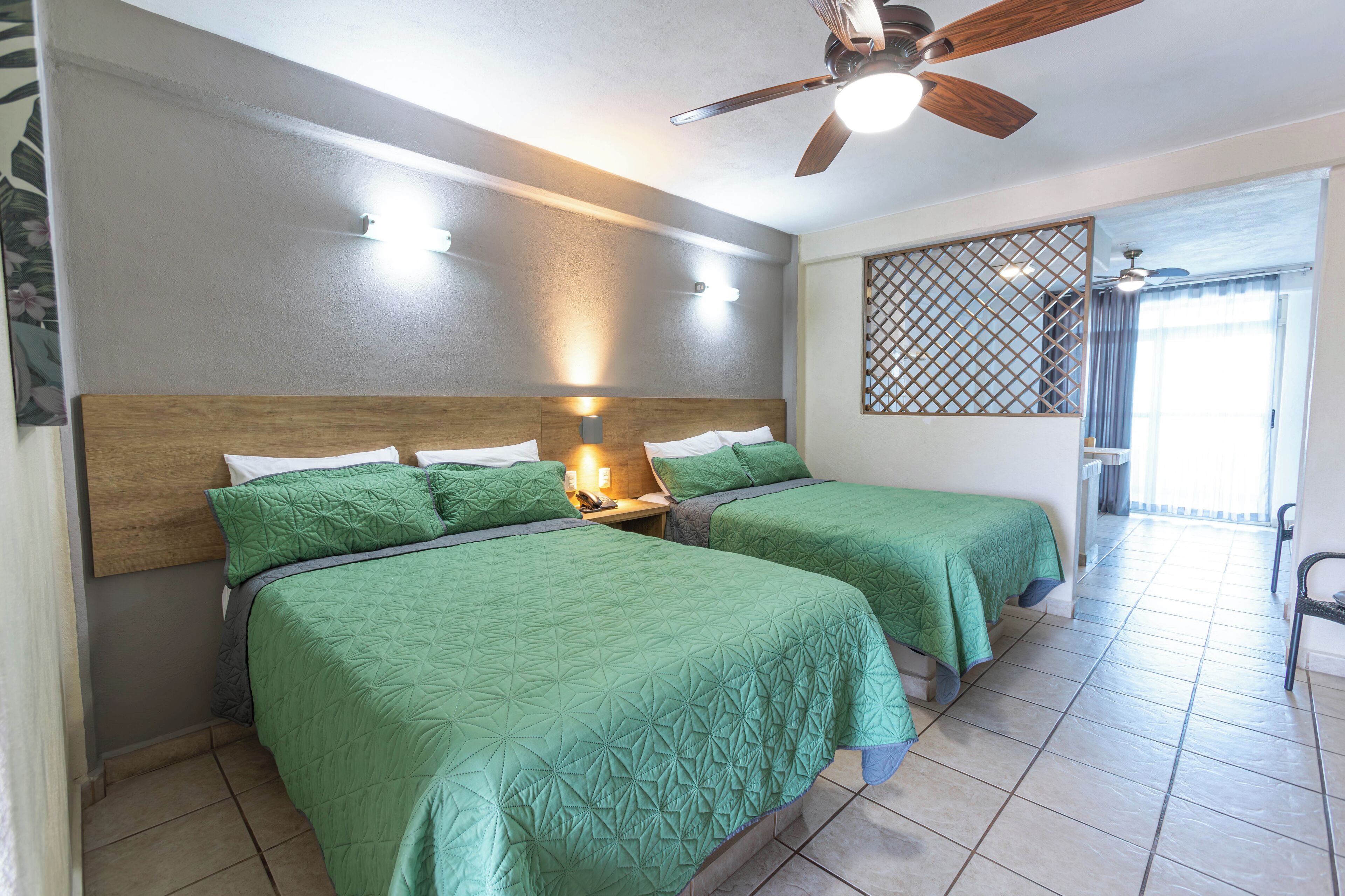 Une chambre d’hôtel avec deux lits, un ventilateur de plafond et une vue sur l’extérieur.