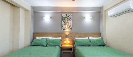 Habitación con dos camas, ventilador de techo, luces fijadas a la pared, un cuadro y un equipo de aire acondicionado.