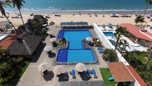 A hotel with a swimming pool, beach view, and thatched-roof structures. - Torreblanca Beach Hotel and Suites Guayabitos - Desayuno y Comida Incluido (Rincón de Guayabitos)