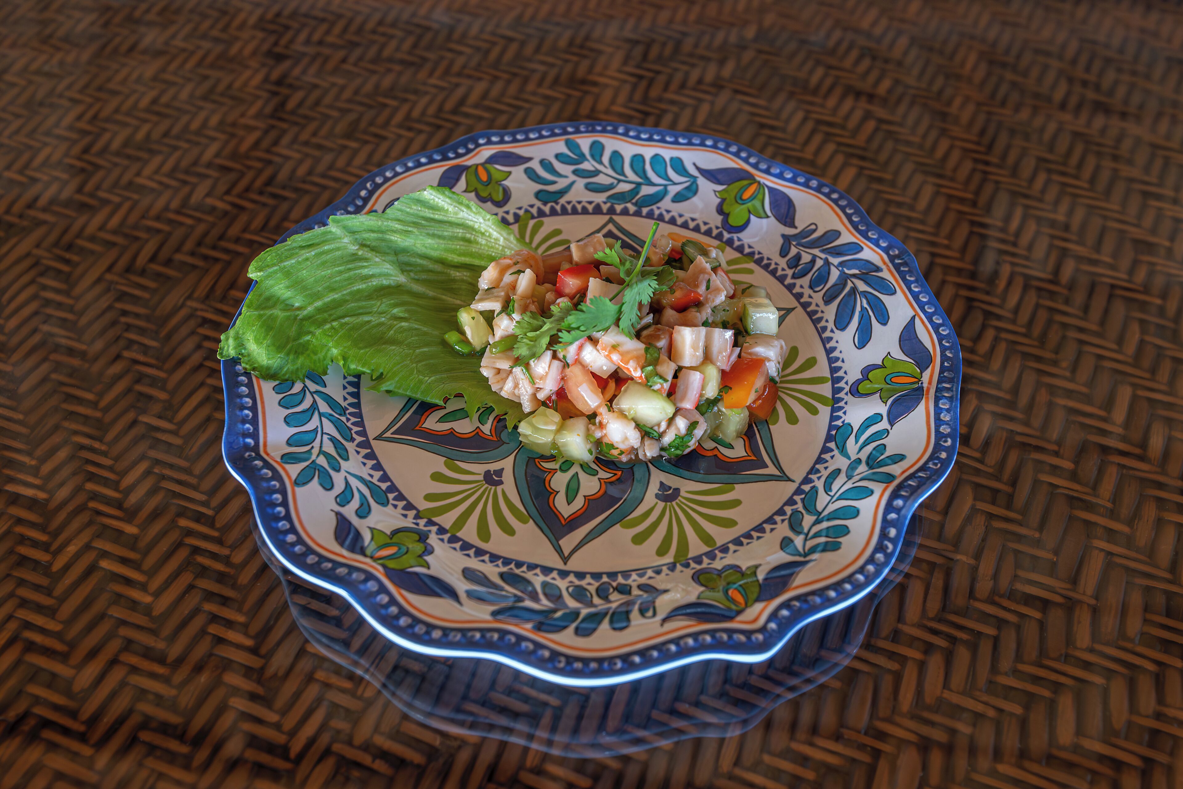 Ensalada de mariscos en un plato decorativo, sobre un mantel tejido.