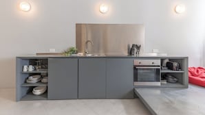 Une cuisine moderne avec des meubles de couleur grise, un four encastré et un évier en acier inoxydable.