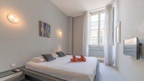 Une chambre à coucher moderne avec un lit, une table de chevet et une fenêtre avec des rideaux.