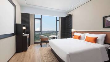 Habitación de hotel con una cama grande, un escritorio, una silla y vistas a la ciudad.