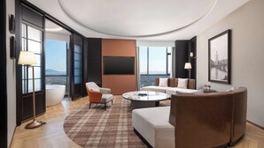 Una habitación de hotel moderna con un ventanal grande, una mesa redonda para café, un sofá y una silla.
