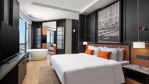 Una habitación de hotel moderna con una cama grande, un televisor de pantalla plana, una bañera y vistas a la ciudad.