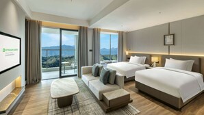 Une chambre d’hôtel moderne dotée d’un grand lit, d’un canapé, d’une petite table et d’un balcon offrant une vue sur la montagne.