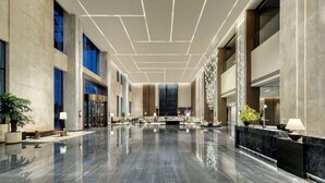 Un hall d’entrée spacieux avec un sol en marbre poli, un espace salon central et un design de plafond moderne.