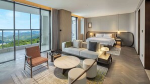 Une chambre d’hôtel moderne dotée d’un grand balcon, d’un lit, d’un canapé, d’une table basse et d’un fauteuil.