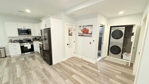A modern kitchen with white cabinets, stainless steel appliances, and a herringbone wood floor. - The Luxury Suite: 1BR Perfect for Long Stays (Paterson)