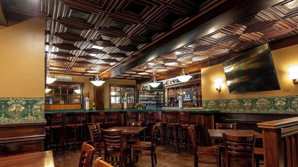 A bar area with wooden furniture and a patterned wall. - Mark Twain Room - Big Tree Inn - In-Room Jacuzzi

 (Geneseo)