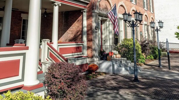 Een gebouw van rode bakstenen met een overdekte veranda, zuilen en een Amerikaanse vlag.