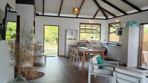 Une cuisine spacieuse dotée d’appareils électroménagers modernes, un coin repas avec des meubles blancs et une grande fenêtre laissant entrer la lumière naturelle.