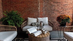 A cozy seating area with wicker furniture, a book, a coffee pot, and a potted plant. - Concord Coach - Big Tree Inn

 (Geneseo)