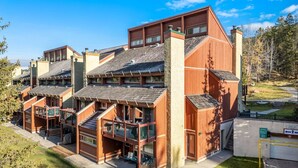 Ein mehrstöckiges Holzgebäude mit Balkonen und einer Garage.