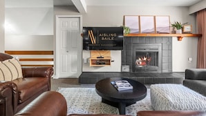 Ein modernes Wohnzimmer mit Kamin, Wand-Fernseher und Ledersofa.