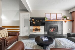 A modern living room with a fireplace, a mounted TV, and a leather sofa. - Free Spirit | Ski-In/Out | Hot Pools | Toby Chair (Panorama)