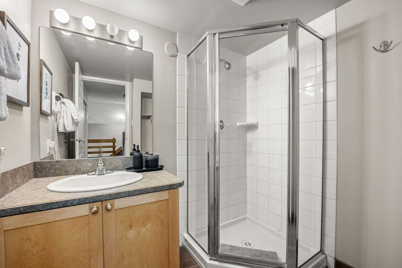 A bathroom with a glass-enclosed shower, a sink, and a vanity with a mirror.