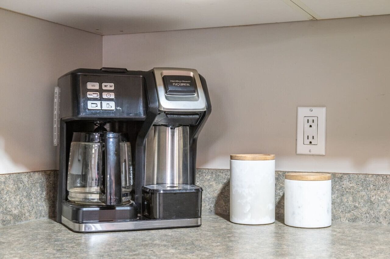 A coffee maker with a control panel and a water reservoir on a kitchen counter.