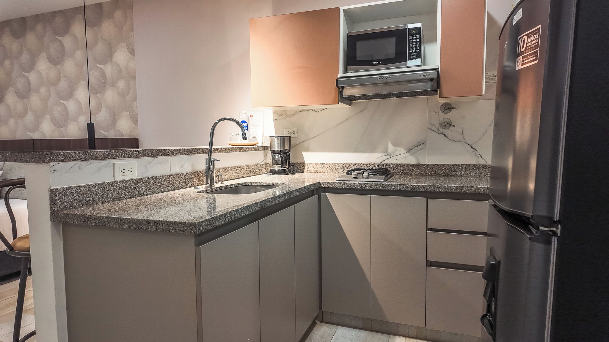 A kitchen with a built-in microwave, a coffee maker, and a stainless steel refrigerator.