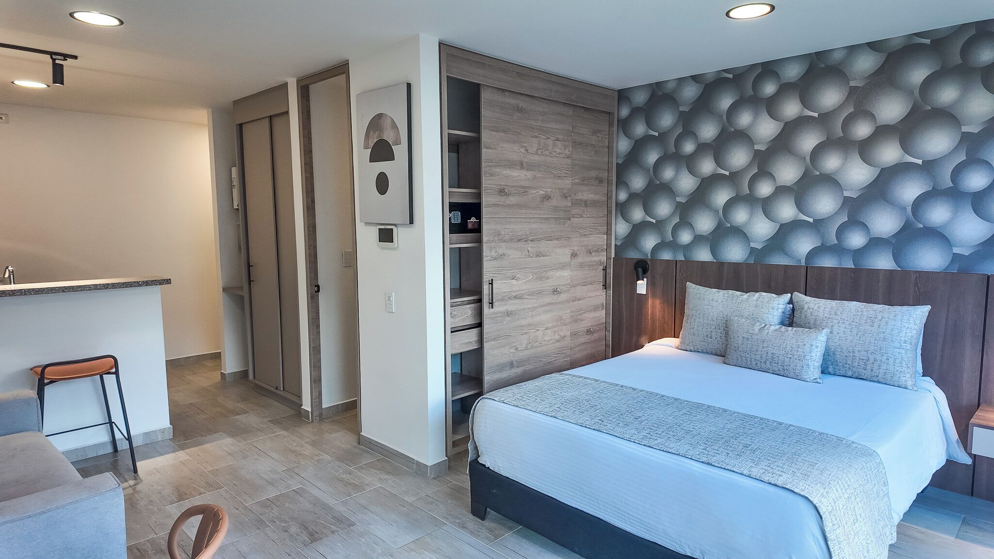 Ein modernes Schlafzimmer mit Bett, Einbauschrank und einer kleinen Küchenzeile.