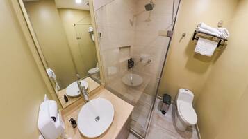Un baño moderno con ducha de vidrio, dos lavamanos y un inodoro.