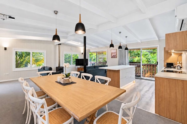 A modern kitchen with a central island, pendant lighting, and a view of greenery outside.