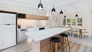 Une cuisine moderne dotée d’un îlot central, de tabourets de bar et de luminaires suspendus.