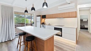 Une cuisine moderne dotée d’un îlot central, de meubles en bois et de luminaires suspendus.