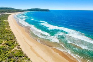 Una playa costera con aguas azul cristalino y un litoral arenoso.