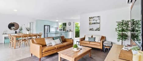 En moderne stue med sofa, sofabord og spiseplads.