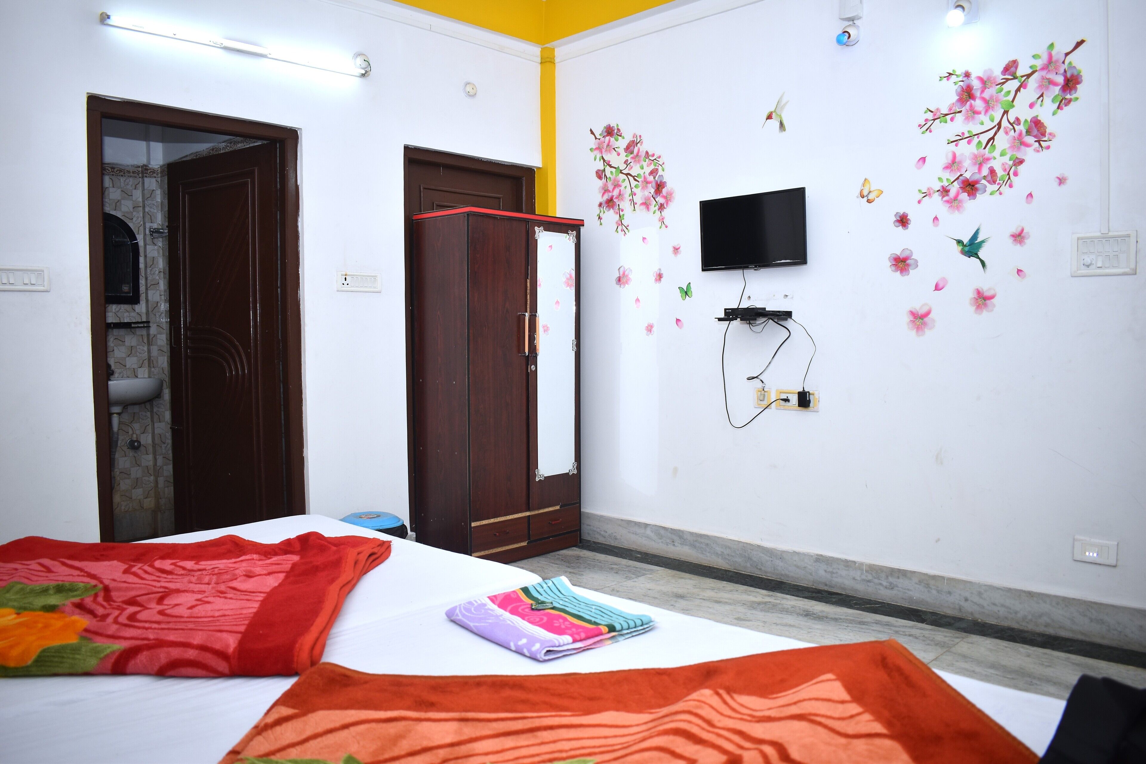A bedroom with a bed, a wardrobe, a TV, and decorative wall stickers.