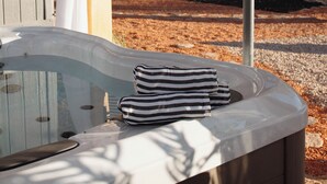 Un jacuzzi con cubierta de madera, una lámpara colgante y vistas a árboles y montañas.