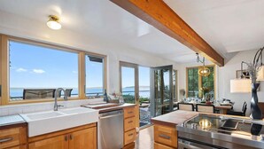 Una cocina moderna con armarios de madera, un lavamanos de acero inoxidable y un amplio ventanal con vista al mar.