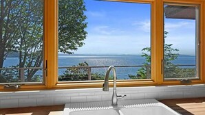 Una cocina con un amplio ventanal que ofrece vistas al mar y a los árboles.
