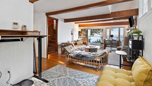 Amplia sala de estar con un ventanal grande, vigas de madera, un sofá, una mesa de centro y una zona de comedor.