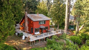 Una cabaña roja con terraza, rodeada de un bosque denso.