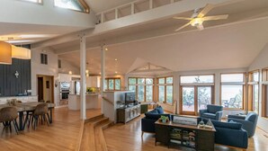 A spacious living area with a dining table, sofas, and a kitchen in the background. - Hood Canal Waterfront Group Retreat (Silverdale)