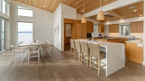 Een moderne keuken met houten kastjes, een centraal kookeiland en hangende verlichting.