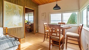 A cozy room with wooden walls, a dining table with chairs, a large window with a view, and a map on the wall. - An Exciting Salish Escape w/ Waterfront View (Kingston)