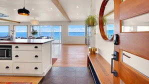 Een moderne keuken met een ruim kookeiland, houten details en uitzicht op de zee.
