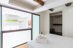 Quarto de hotel com cama, banheiro com espelho e guarda-roupa.