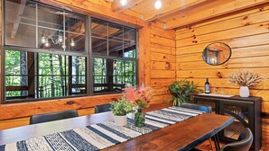 A wooden cabin interior with a dining table, chairs, a potted plant, and a mirror on the wall. - Perfect for couples! Modern, Private + Hot Tub, Fire pit, Fireplace & King Bed (Maggie Valley)