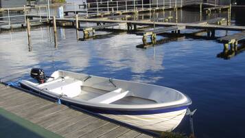 A small motorboat docked at a wooden pier with a clear view of the water and a dock extending into the distance.