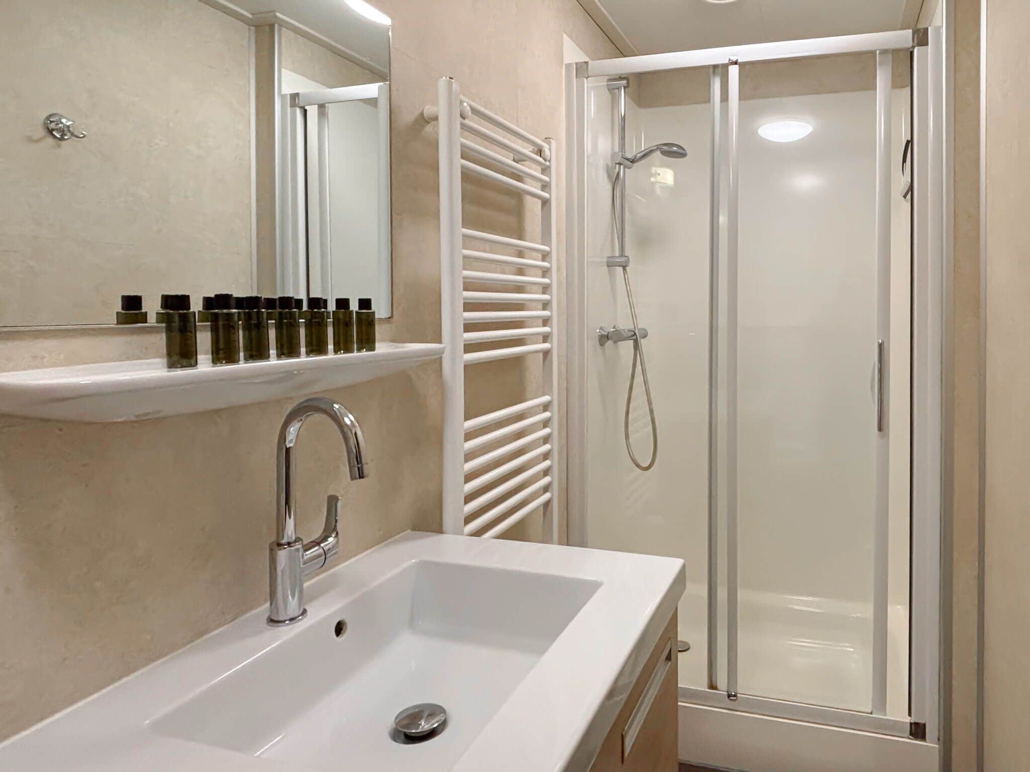 A modern bathroom with a white sink, a mirror, and a glass-enclosed shower.