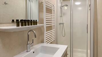A modern bathroom with a white sink, a mirror, and a glass-enclosed shower.