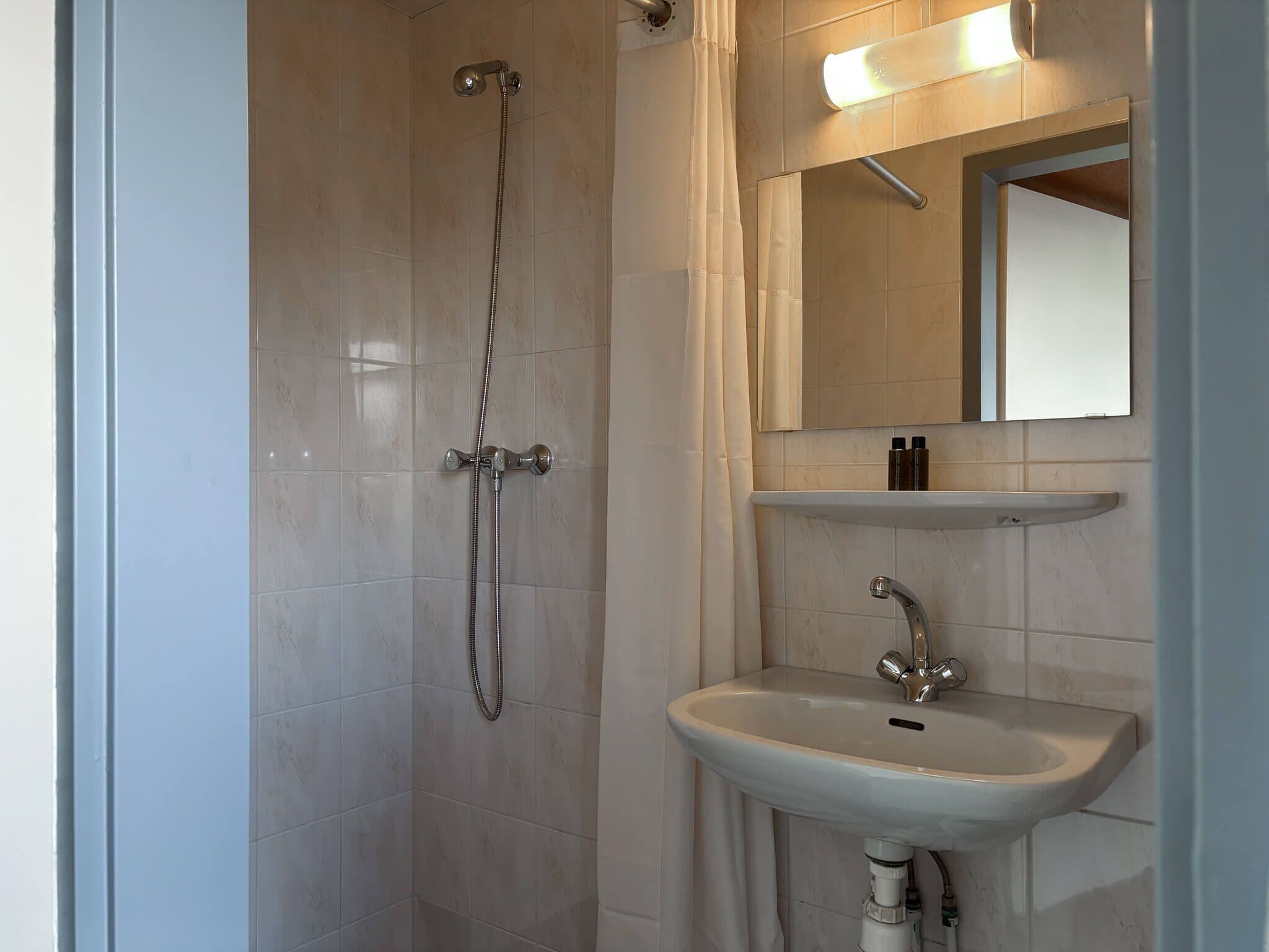 Ein Badezimmer mit Dusche, Waschbecken und Spiegel.