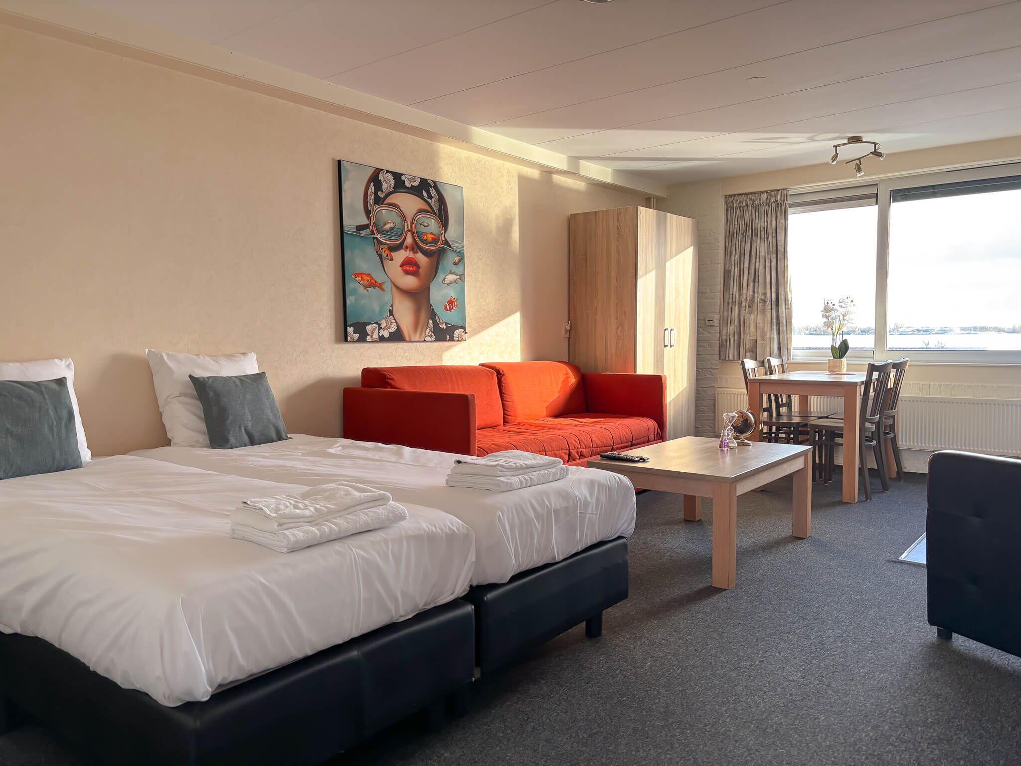 Une chambre d’hôtel avec un lit, un canapé, une table et une vue sur l’extérieur.