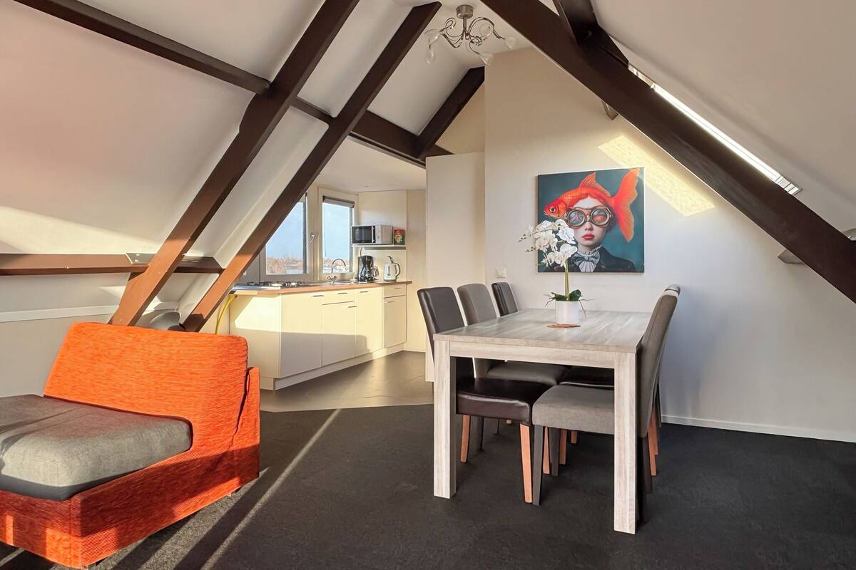 A modern loft apartment with a dining area, kitchen, and a view of the outdoors.